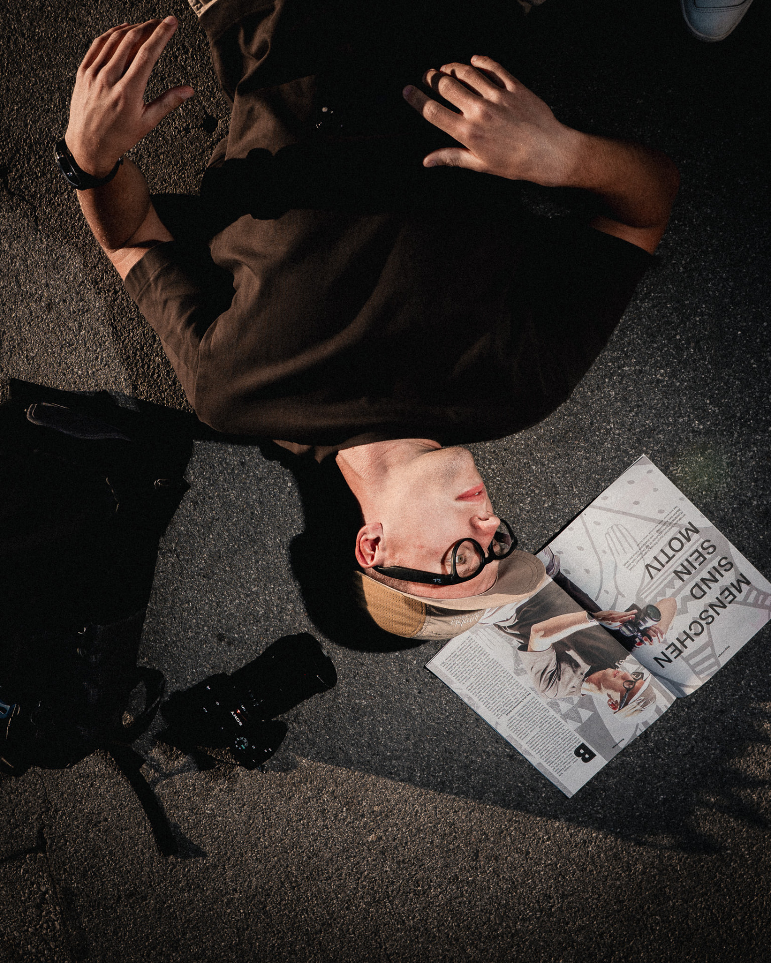 Bartosz Dulinski lying on the pavement with his camera, photographed from above