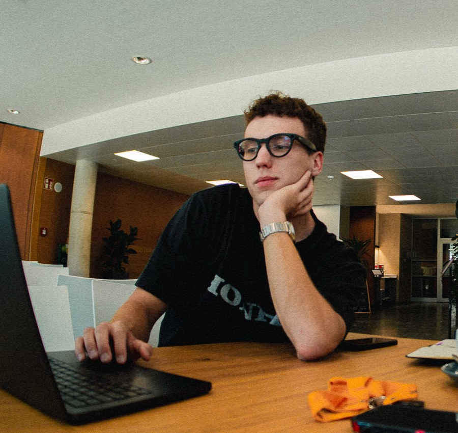 Bartosz Dulinski at a wooden desk, resting his chin on his hand while looking at his open laptop